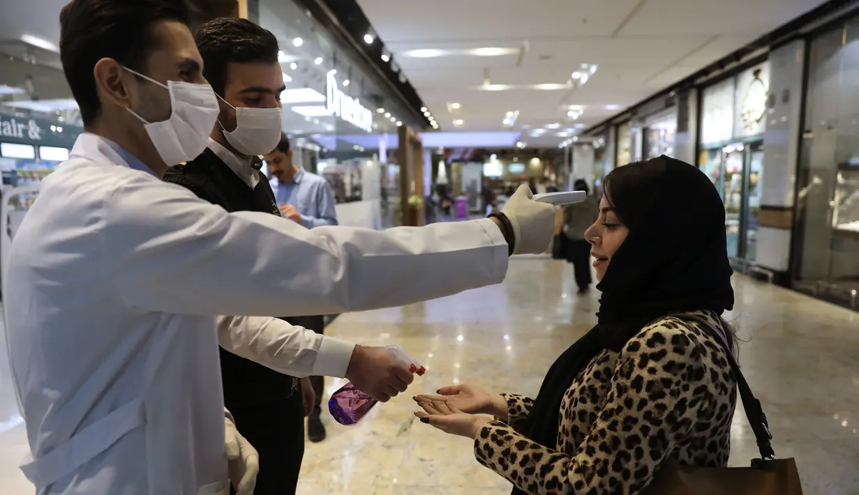 Seorang wanita saat diperiksa suhu tubuhnya dan tangannya ketika memasuki Pusat Perbelanjaan Palladium, di Teheran utara, Iran, Selasa (3/3/2020). Demam yang merupakan salah satu gejala dari infeksi corona menjadikan termometer sebagai salah satu alat untuk mendeteksi. (AP Photo/Vahid Salemi)