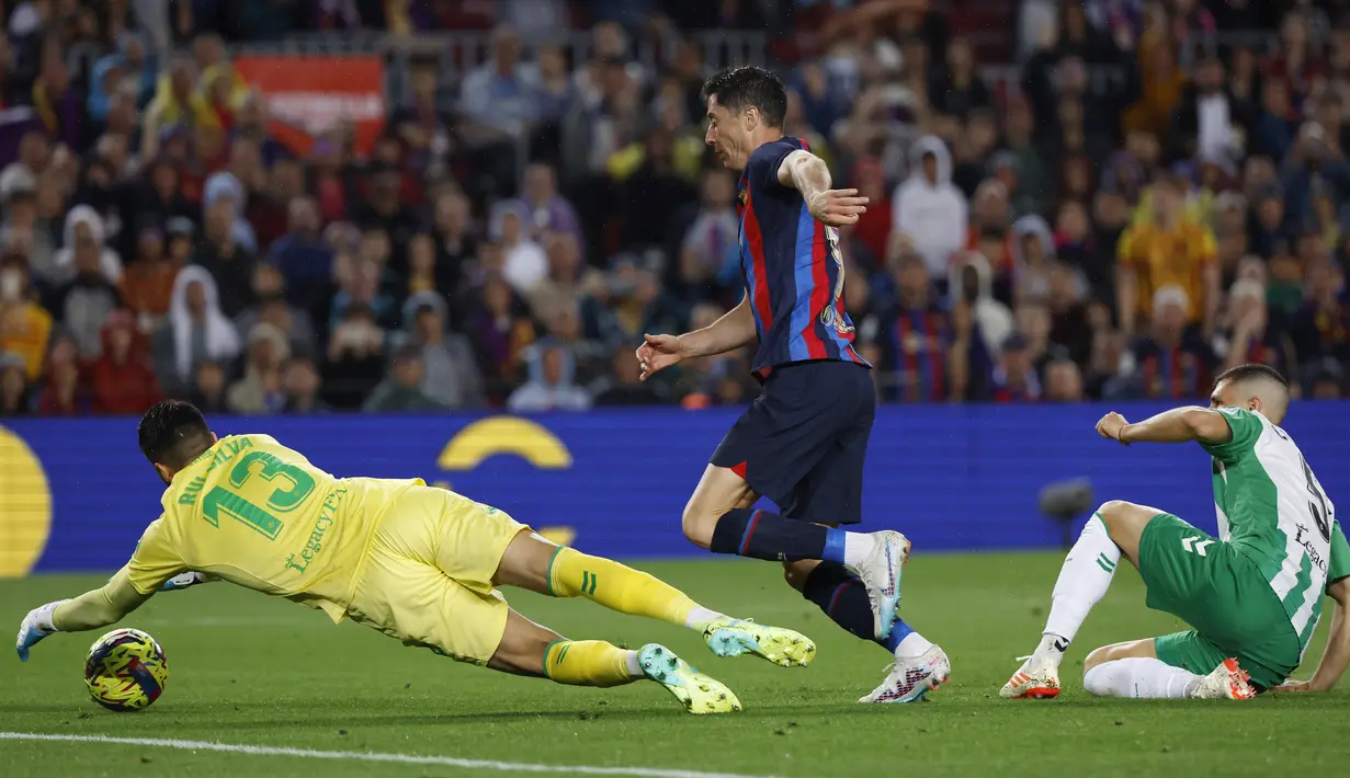 Pemain Barcelona, Robert Lewandowski, berusaha mencetak gol ke gawang Real Betis pada laga Liga Spanyol di Stadion Camp Nou, Minggu (30/4/2023). Empat gol Barcelona dicetak Andreas Christensen, Robert Lewandowski, Raphinha dan gol bunuh diri Guido Rodriguez. (AP Photo/Joan Monfort)