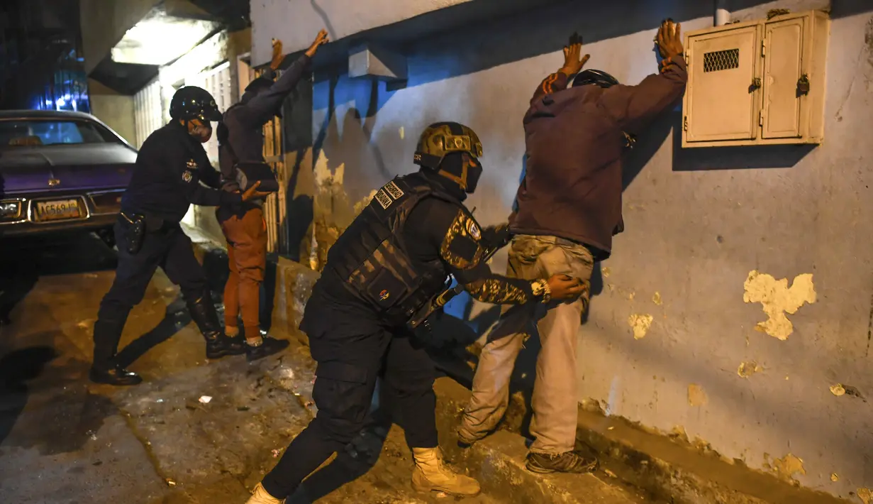 Anggota polisi menggeledah orang-orang saat operasi di tengah pandemi COVID-19 di Los Teques, negara bagian Miranda, Venezuela, 20 Maret 2021. Di Miranda ada pembatasan keluar sejak pukul 18.00 dan perintah penutupan toko pada pukul 16.00 di tengah gelombang kedua pandemi. (Federico PARRA/AFP)