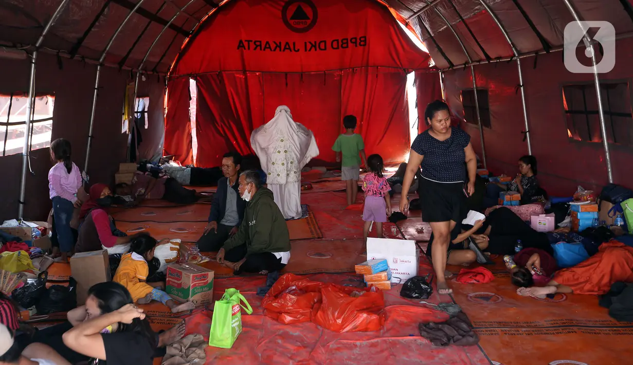 Petugas PPSU berusaha menyiramkan air mencegah pasir terbang terbawa angin. (Liputan6.com/Johan Tallo)