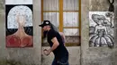 Seorang pria berjalan melewati mural yang terinspirasi oleh karya Velazquez "Las Meninas" selama festival seni jalanan tahunan di Ferrol, Spanyol, Minggu (2/9). Festival ini untuk menghirup kehidupan baru di lingkungan yang sekarat. (MIGUEL RIOPA/AFP)