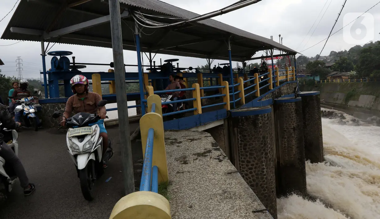 Pengendara melintasi di Bendung Katulampa, Bogor, Jawa Barat, Jumat (19/2/2021). Meski sempat mengalami kenaikan debit air pada Jumat (19/2) pagi, namum sekitar pukul 15.00 WIB, debit air di Bendung Katulampa berada di zona hijau dengan ketinggian sekitar 50 cm. (Liputan6.com/Helmi Fithriansyah)