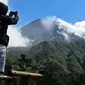 Seorang pria mengambil gambar Gunung Merapi di Cangkringan, Indonesia, Selasa, (22/5). Pihak berwenang meningkatkan kewaspadaan terhadap Gunung Merapi yang bergejolak di pulau Jawa. (AP Photo/A.K. Hendratmo)