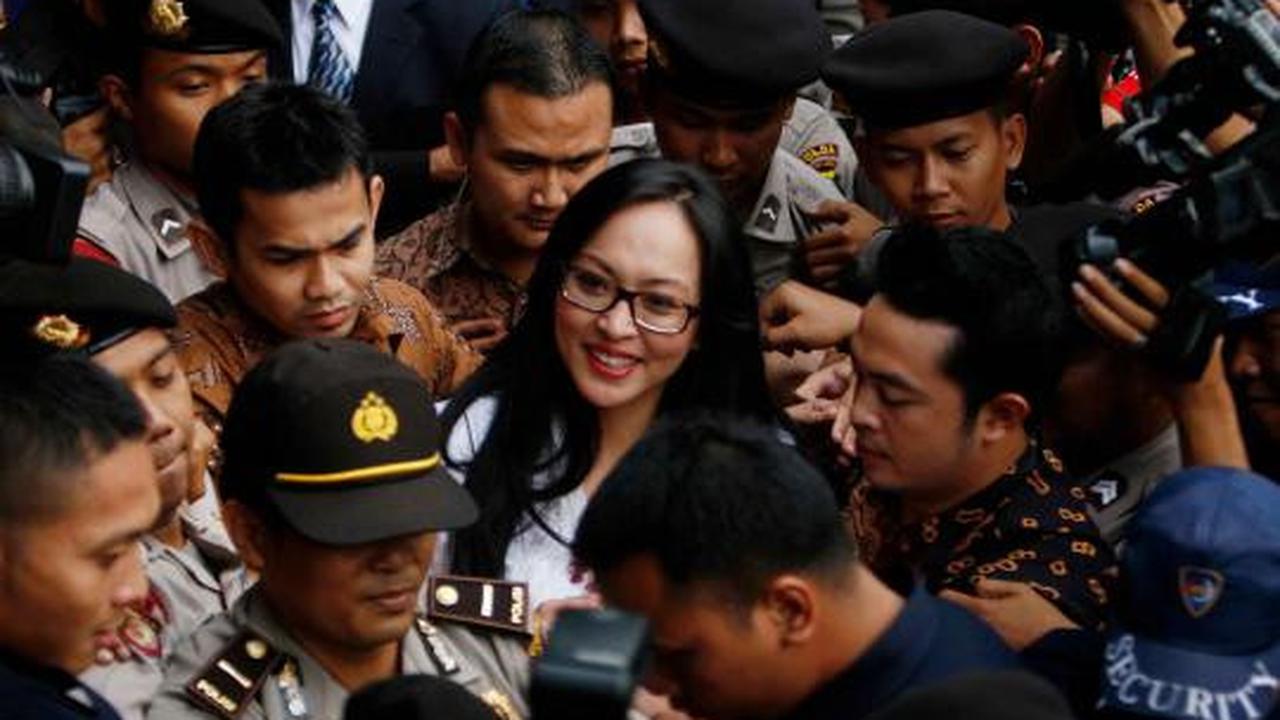 Angelina Sondakh tersenyum saat dikawal petugas keamanan KPK dan polis 