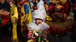 Seorang anak yang mengenakan pakaian badut ikut serta dalam parade badut tahunan di Sesimbra, Portugal pada Senin (4/3/2019). Tidak hanya orang dewasa anak-anak pun ikut merias diri menjadi badut. (PATRICIA DE MELO MOREIRA / AFP)