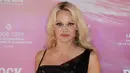 Pamela Anderson berpose saat menghadiri Rock My Swim Fashion Show di Paris, Sabtu (8/7). Pamela mengenakan gaun hitam berkilauan yang menunjukkan kegemarannya menonjolkan fisik rahangnya. (AFP Photo)