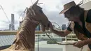 David Marriott berpose dengan kuda kertasnya Russell di kamar hotelnya di Brisbane, Australia, 3 April 2021. Direktur seni di iklan TV itu juga membuat pakaian koboi, celana topi dan juga rompi kantong kertas makanannya yang dikirimkan selama menjalani karantina. (David Marriott via AP)