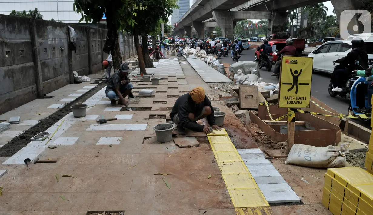 Pekerja menyelesaikan proyek revitalisasi trotoar di kawasan Kuningan, Jakarta, Senin (4/11/2019). Proyek revitalisasi trotoar DKI Jakarta kini tengah dibahas bersama Komisi D DPRD dalam rapat Kebijakan Umum APBD Prioritas Plafon Anggaran Sementara Tahun 2020. (merdeka.com/Iqbal Nugroho)