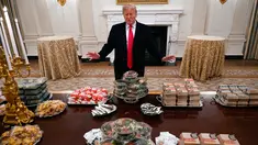 Presiden Amerika Serikat (AS) Donald Trump berpose dengan meja penuh makanan cepat saji di Gedung Putih, Washington, Senin (14 /1). Jamuan Trump ini untuk menyambut juara nasional sepak bola antarkampus, Clemson Tigers. (AP Photo/Susan Walsh)