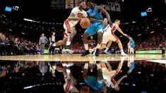 Pebasket Miami Heat, James Johnson (kiri) mencoba melewati adangan pebasket Hornets, Johnny O'Bryant III #8  pada laga NBA pre-season di American Airlines Arena, Miami, (9/10/2017). Miami Heat menang 109-106. (Mike Ehrmann/Getty Images/AFP)