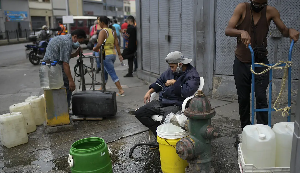 Warga memanfaatkan hidran kebakaran untuk mengisi wadah mereka dengan air di lingkungan San Juan di Caracas, Venezuela (19/1/2021). Venezuela merupakan negara dengan salah satu cadangan minyak terbesar di dunia. (AP Photo/Matias Delacroix)