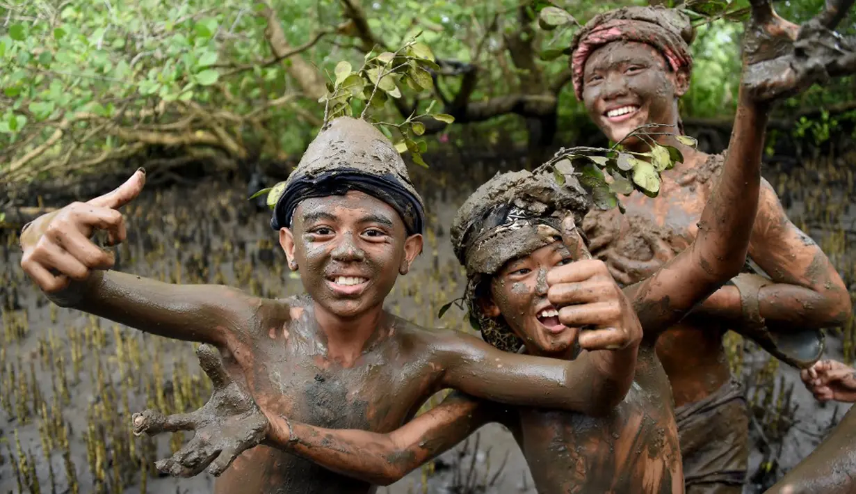 Anak-anak berpose saat mereka mengambil bagian dalam tradisi mandi lumpur yang dikenal sebagai Mebuug-buugan di Desa Kedonganan, Bali, 4 Maret 2022. Mebuug-buugan diadakan sehari setelah Nyepi yang bertujuan untuk menetralkan sifat buruk. (SONY TUMBELAKA/AFP)
