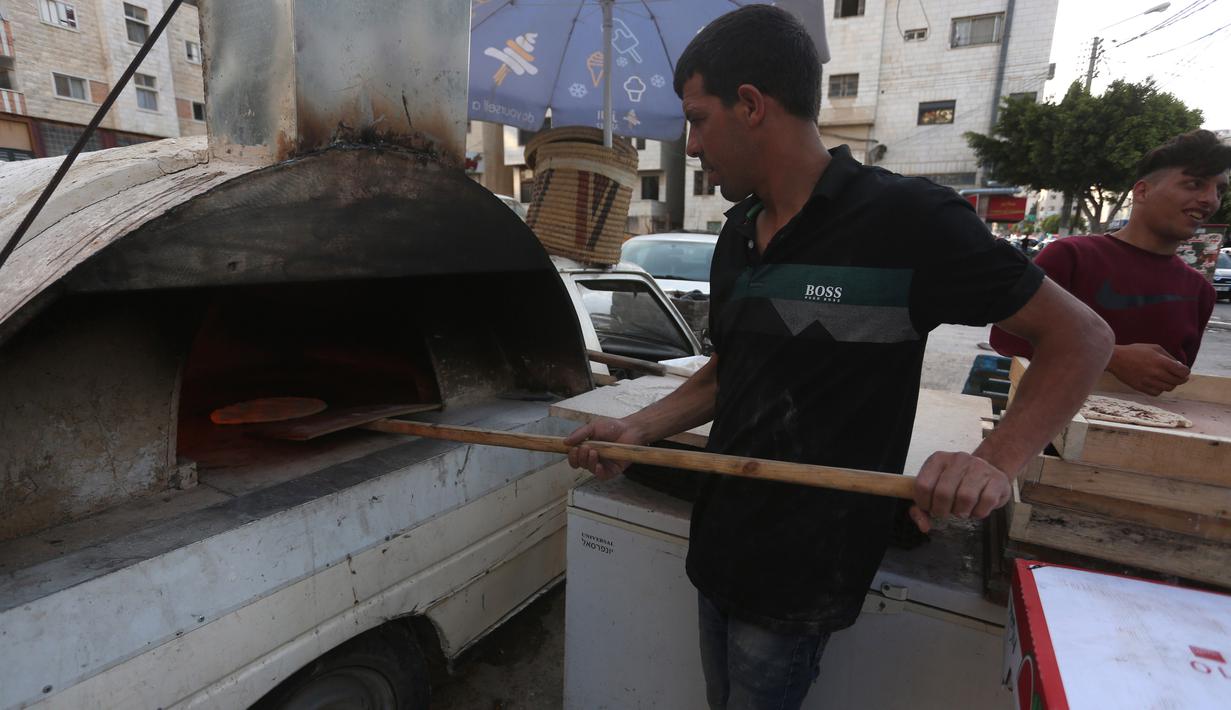 Penjual roti Palestina Mohammed Abu Saud menyiapkan roti di Kota Nablus, Tepi Barat, (3/5/2020). Abu Saud, yang kehilangan pekerjaannya sebagai pekerja transportasi karena kebijakan lockdown selama pandemi COVID-19, memutuskan bekerja sebagai penjual roti keliling. (Xinhua/Ayman Nobani)