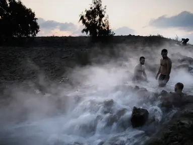 Wisatawan berendam di kolam air panas di utara Dataran Tinggi Golan yang diduduki Israel, 4 November 2017. Air mengalir dari aliran pipa pengeboran di Lembah Hula yang merupakan upaya mengurangi kekeringan di kawasan pertanian. (ENAHEM KAHANA/AFP)