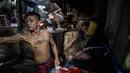 Narapidana memasak makan malam sementara kawannya mandi di dalam penjara Quezon City di Manila, Filipina, 21 Juli 2016. Kondisi sanitasi penjara Quenzon City sangat buruk, hanya terdapat satu toilet yang digunakan hingga 130 narapidana. (Noel Celis/AFP)