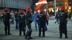 Seorang suporter Spartak Moskow berjalan melewati polisi di Stadion San Mames, Bilbao, Spanyol, Kamis (22/2). Polisi Inocencio Arias Garcia meninggal dunia karena mengalami serangan jantung saat bentrok. (ANDER GILLENEA/AFP)