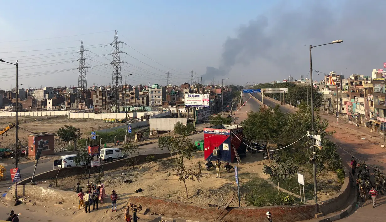 Asap hitam membumbung setelah toko-toko dibakar dalam bentrok antara massa pendukung dan penentang Undang-Undang Kewarganegaraan baru di Bhajanpura, New Delhi, India, Selasa (25/2/2020). Kekerasan meletus di berbagai wilayah timur laut New Delhi. (AP Photo/Sheikh Saaliq)