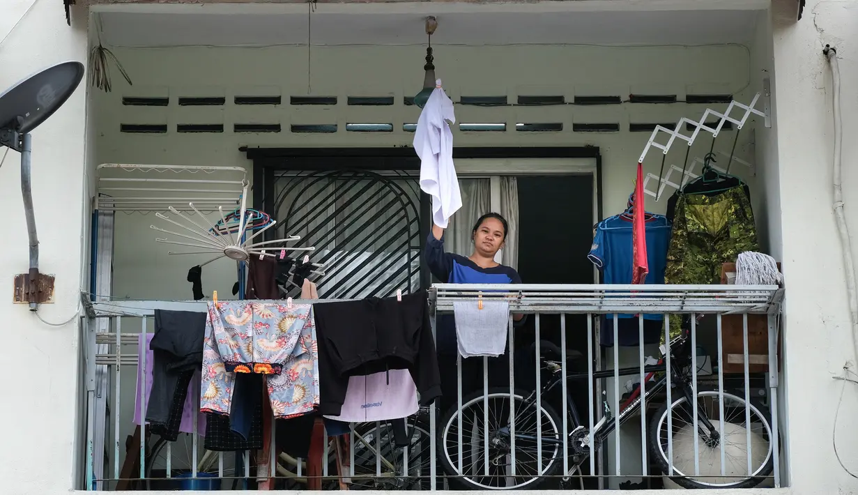 Ibu tunggal Tilda Kalaivani melambaikan kemeja yang digunakan sebagai bendera putih di apartemen sewaannya di Kuala Lumpur pada 6 Juli 2021. Akibat lockdown nasional, banyak keluarga berpenghasilan rendah yang terdampak oleh pandemi COVID-19 semakin kesulitan dalam menjalani hidup. (Mohd RASFAN/AFP)