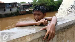 Seorang anak di bantaran kali Ciliwung, Kampung Pulo, Jakarta Timur, Sabtu (12/3). Warga memanfaatkan lahan di aliran sungai untuk tempat bermain karena minimnya lahan kosong di sekitar wilayah itu.(Liputan6.com/Gempur M Surya)
