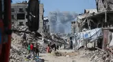 Asap mengepul ke arah utara menjadi latar ketika warga Palestina bergerak melalui Jabalia meninggalkan Jalur Gaza utara menuju Kota Gaza pada 19 Mei 2025. (Bashar TALEB/AFP)