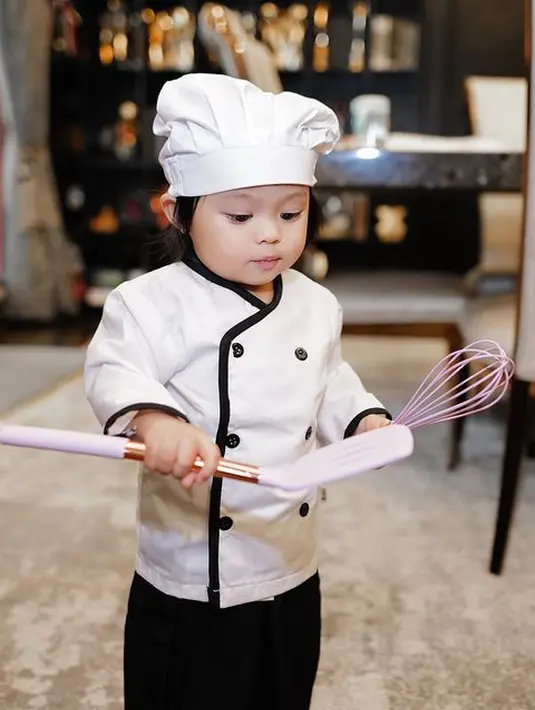 <p>Mengenakan pakaian cheff lengkap dengan penutup kepalanya. Sedangkan ditangannya tampak memegang atat pengaduk hingga alat untuk membalik gorengan. [Instagram/attahalilintar]</p>