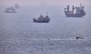 Sebuah perahu kecil berlayar melewati kapal kargo dan kapal komersial lainnya yang sedang berlabuh di Selat Hormuz, di lepas pantai Bandar Abbas, Iran, Rabu, 5 Agustus 2026. (Amirhosein Khorgooi/ISNA via AP)