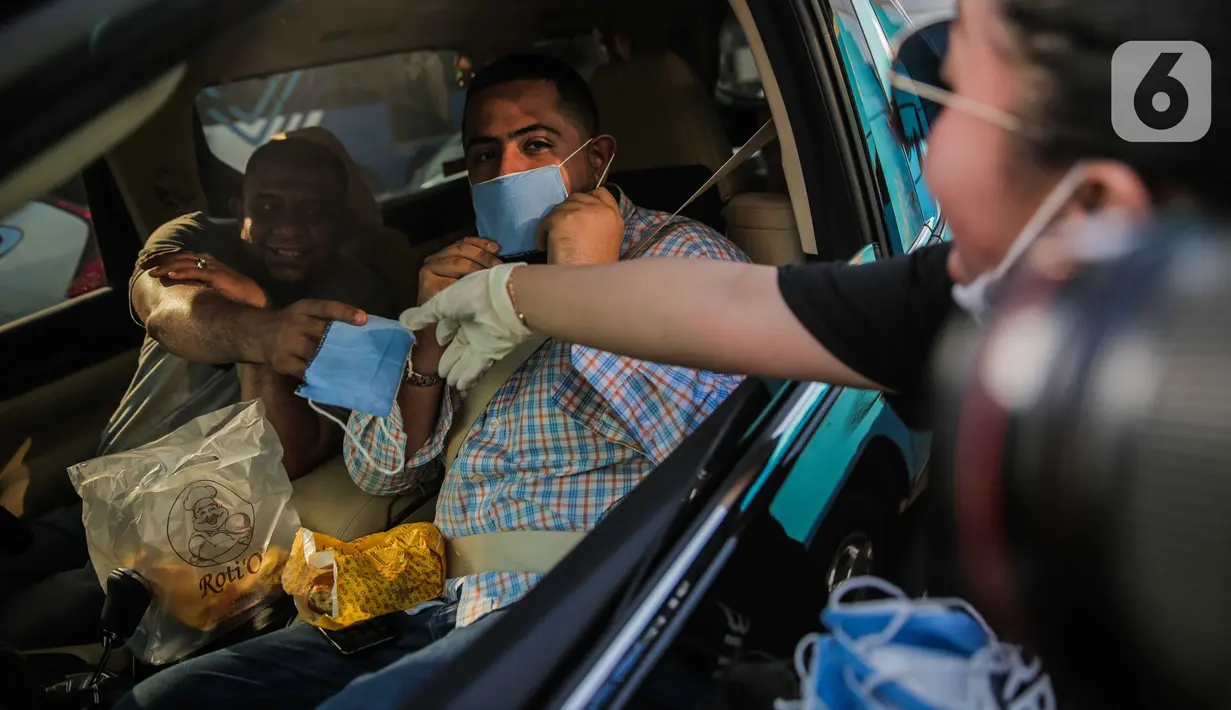 Relawan membagikan masker kepada pengemudi mobil di Bundaran HI, Jakarta, Selasa (17/3/2020). Sebanyak 3.000 masker dibagikan gratis kepada pengguna jalan sebagai bentuk keprihatinan sekaligus berpartisipasi dalam upaya mencegah penyebaran virus corona COVID-19. (Liputan6.com/Faizal Fanani)