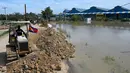 Buldoser mendorong tanah mencaegah kenaikan air banjir di Phnom Penh, Kamboja (26/10/2021). Kementerian Sumber Daya Air dan Meteorologi telah mengeluarkan pemberitahuan pada hari Senin tentang situasi cuaca, mengkonfirmasikan risiko banjir di 14 ibu kota dan provinsi Kamboja. (AFP/Tang Chhin Sothy)