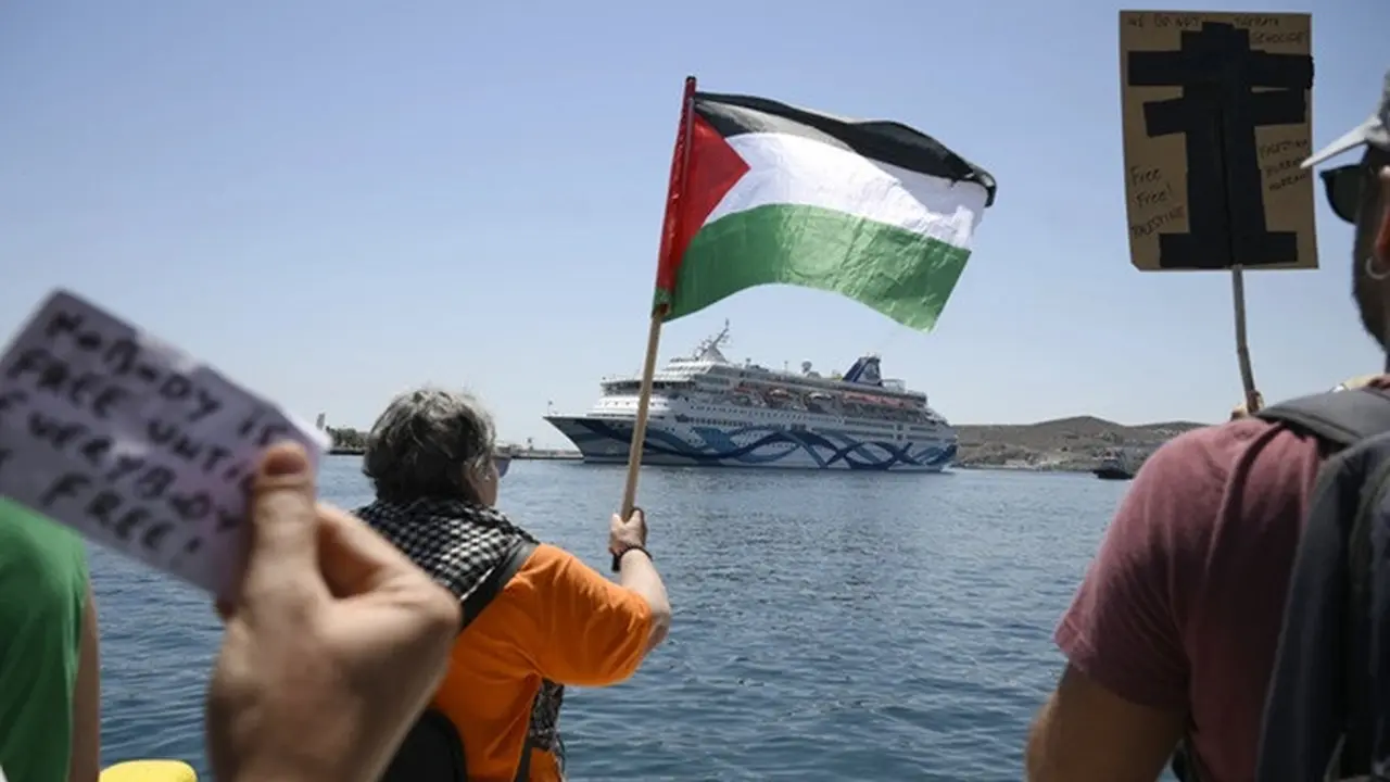 Seorang pengunjuk rasa mengibarkan bendera Palestina saat massa melakukan unjuk rasa di depan kapal pesiar yang membawa turis asal Israel dan berusaha mendekati Pulau Syros di Laut Aegea, Yunani, pada Selasa (22/7/2025).