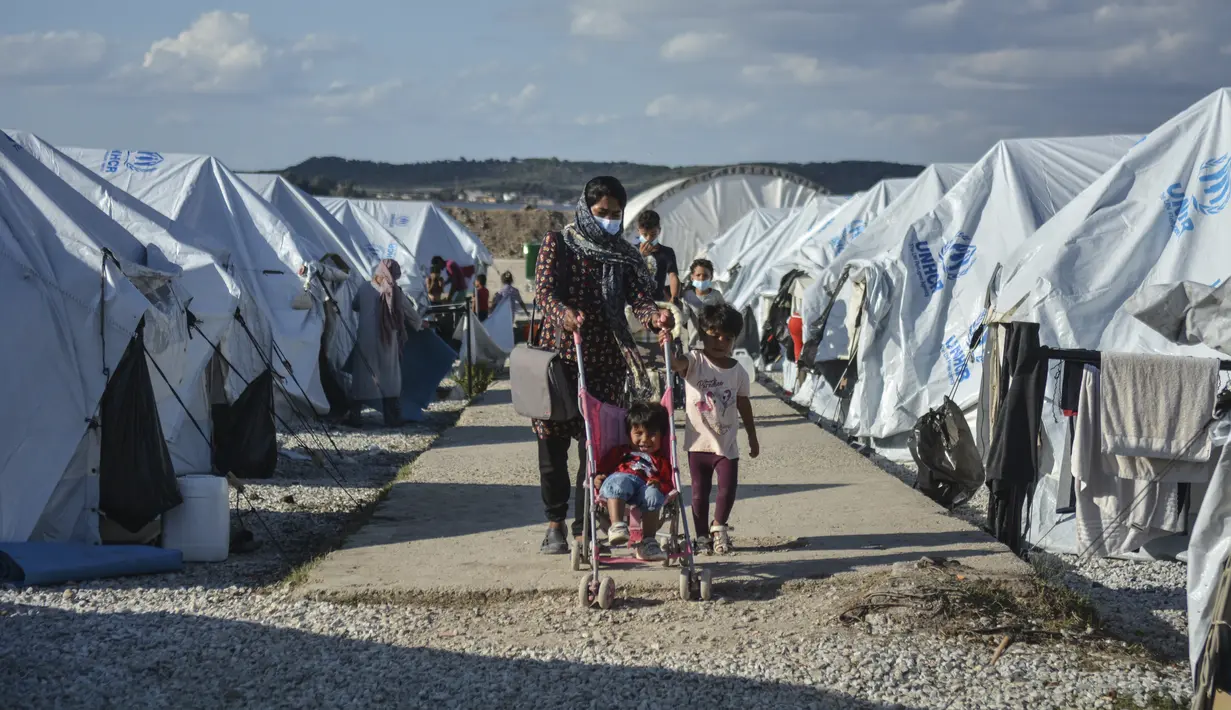 Migran berjalan setelah hujan badai di kamp pengungsi Kara Tepe, di timur laut pulau Lesbos, Aegean, Yunani (14/10/2020).  Sekitar 7.600 pengungsi dan migran telah menetap di kota tenda baru setelah kebakaran berturut-turut pada tanggal 14 September. (AP Photo/Panagiotis Balaskas)