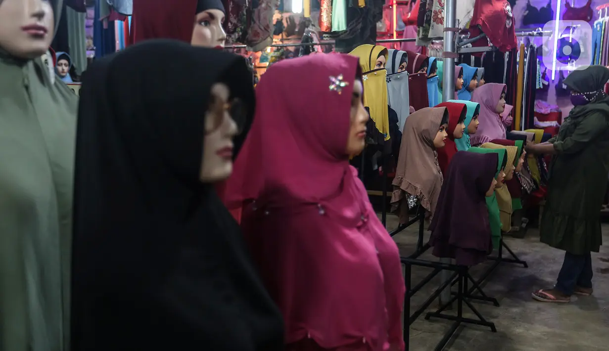 Pedagang gamis dan baju anak menunggu pembeli di kiosnya di pasar Parung, Bogor, Jawa Barat, Kamis (18/2/2021). Akibat menurunnya omset penjualan gamis dan baju anak selama pandemi COVID-19, pedagang rela menurunkan harga agar menarik perhatian pembeli. (Liputan6.com/Johan Tallo)