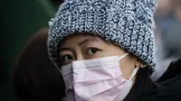 Seorang perempuan mengenakan masker penutup mulut setibanya di stasiun kereta api Beijing untuk mudik Tahun Baru Imlek pada Selasa (21/1/2020). Wabah virus korona seperti SARS yang menyebar di China dan mencapai tiga negara Asia lainnya bisa menular dari manusia ke manusia. (NICOLAS ASFOURI/AFP)