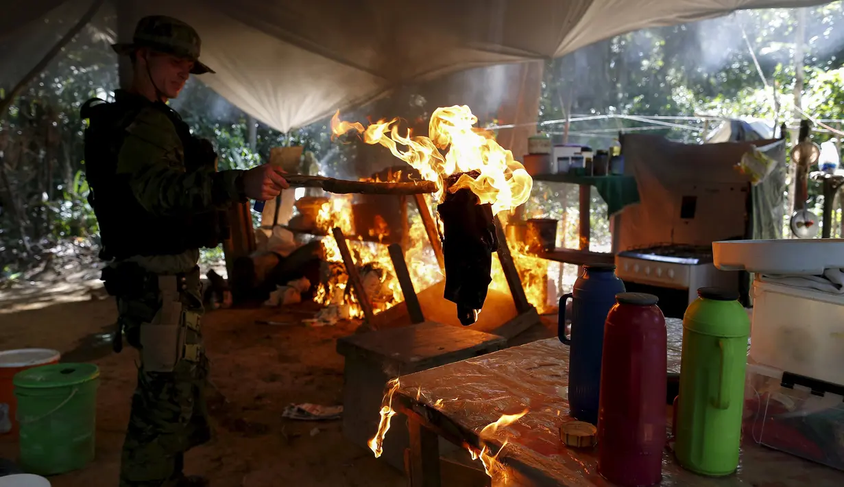 Petugas membakar sebuah kamp penambang liar selama operasi di perairan hutan hujan Amazon, Roraima, Brasil (16/4).Daerah Yanomami memiliki luas 9,5 juta hektar dan ditinggali oleh 27.000 orang Indian/suku Yanomami. (REUTERS / Bruno Kelly)