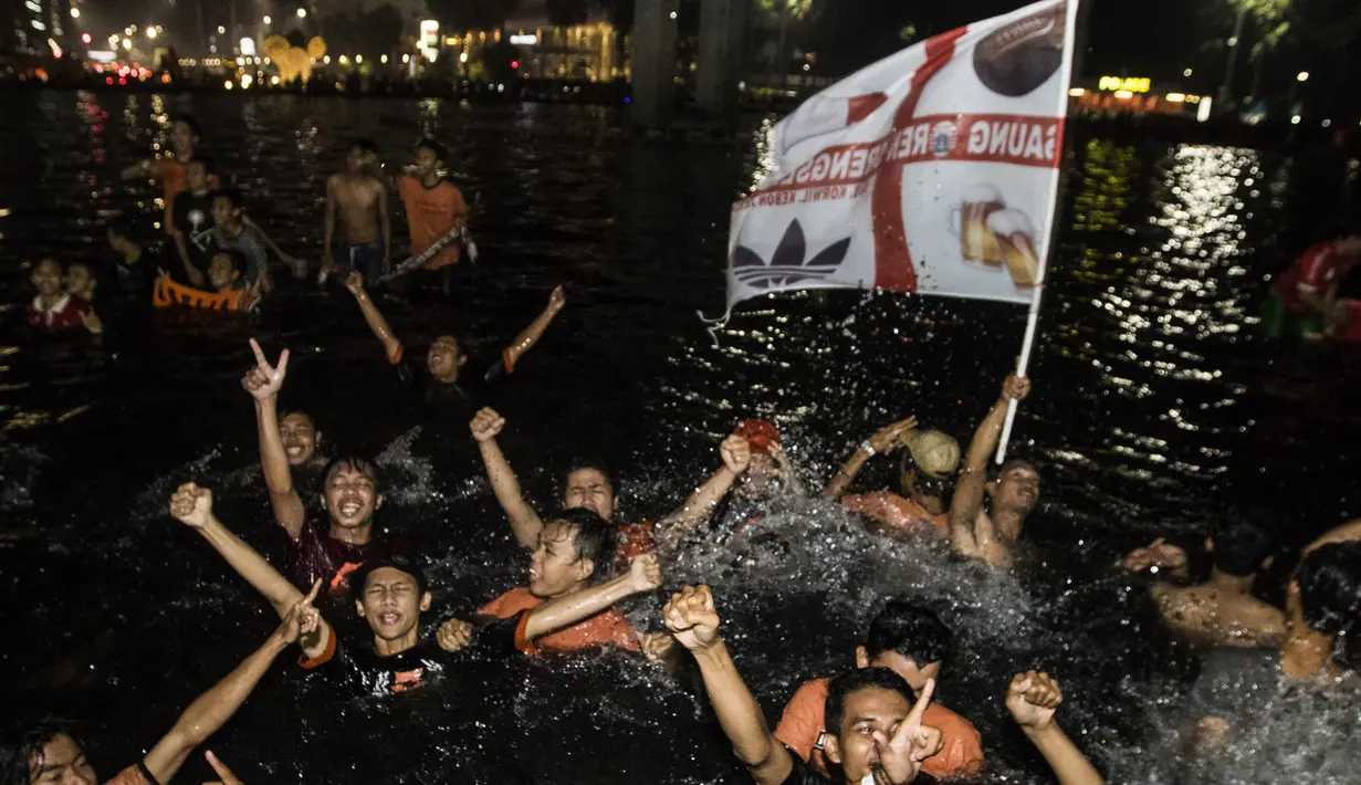 Suporter Persija Jakarta, The Jakmania, berenang saat merayakan pesta juara Liga 1 di Bundaran Hotel Indonesia, Jakarta, Minggu (9/12). Persija unggul satu poin dari PSM Makassar di puncak klasemen. (Bola.com/Vitalis Yogi Trisna)