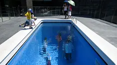 Pengunjung melihat karya seni Swimming Pool dalam sebuah pameran bertajuk "The Confines of the Great Void" di Museum CAFA, Beijing, 23 Juli 2019. Karya seni buatan seniman Argentina, Leandro Erlich ini tampak seperti kolam renang pada umumnya yang penuh dengan air. (WANG Zhao/AFP)