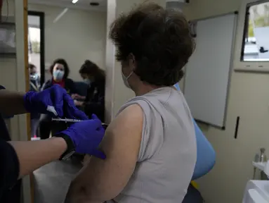 Warga disuntik vaksin COVID-19 Pfizer-BioNTech di dalam van yang digunakan sebagai unit vaksinasi bergerak di pelabuhan Piraeus, Athena, Senin (13/12/2021). Yunani meningkatkan vaksinasi kampanye menjelang liburan Natal ketika negara itu bergulat dengan lonjakan infeksi. (AP/Thanassis Stavrakis)