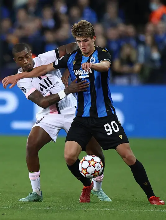 Pemain Paris Saint-Germain Presnel Kimpembe berebut bola dengan pemain Club Brugge Charles De Ketelaere (kanan) pada pertandingan Grup A Liga Champions di Stadion Jan Breydel, Bruges, Belgia, Rabu (15/9/2021). Pertandingan berakhir imbang 1-1. (KENZO TRIBOUILLARD/AFP)