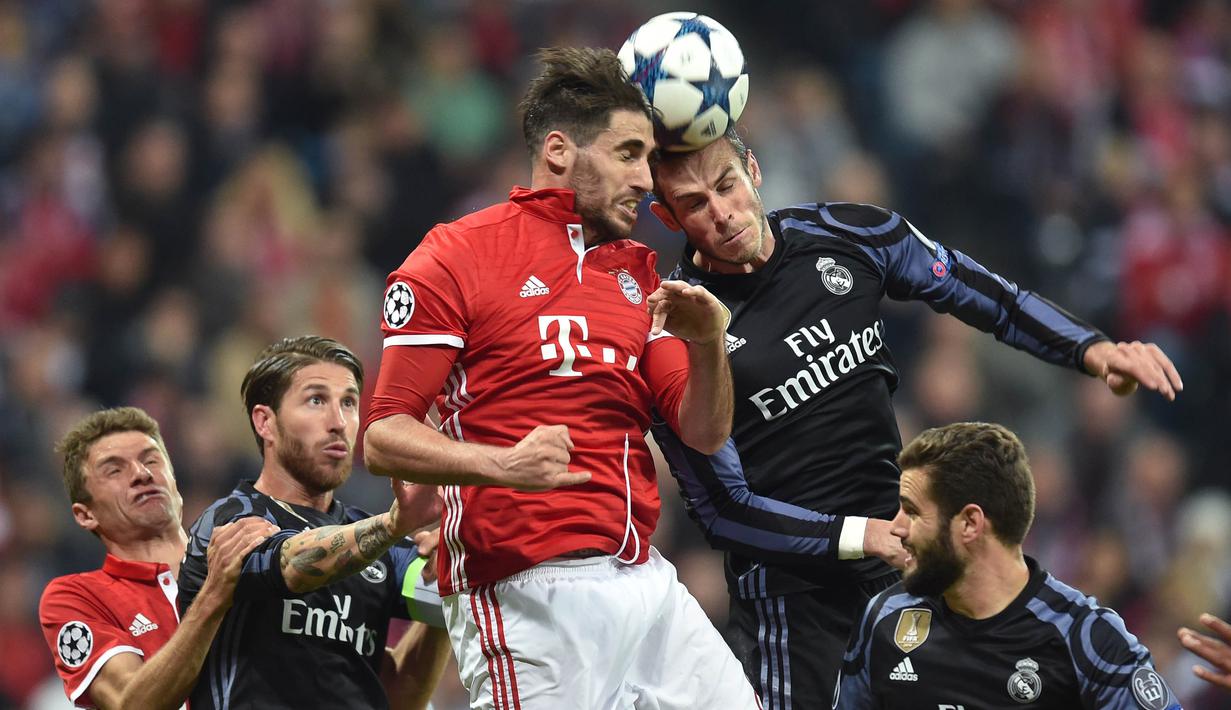 Gelandang Bayern Munchen, Javi Martinez, duel udara dengan striker Real Madrid, Gareth Bale. Pada laga tersebut Real Madrid menguasi pertandingan dengan 51 persen penguasaan bola sementara Bayern Munchen 49 persen. (AFP/Christof Stache)