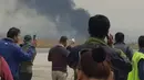 Asap tebal membungbung saat pesawat jatuh dan terbakar di dekat Bandara Internasional Kathmandu, Nepal, Senin (12/3). Menurut manajer bandara, kecelakaan diduga karena pesawat mendekati landasan pacu dari arah yang salah. (Nitin KEYAL/AFP)