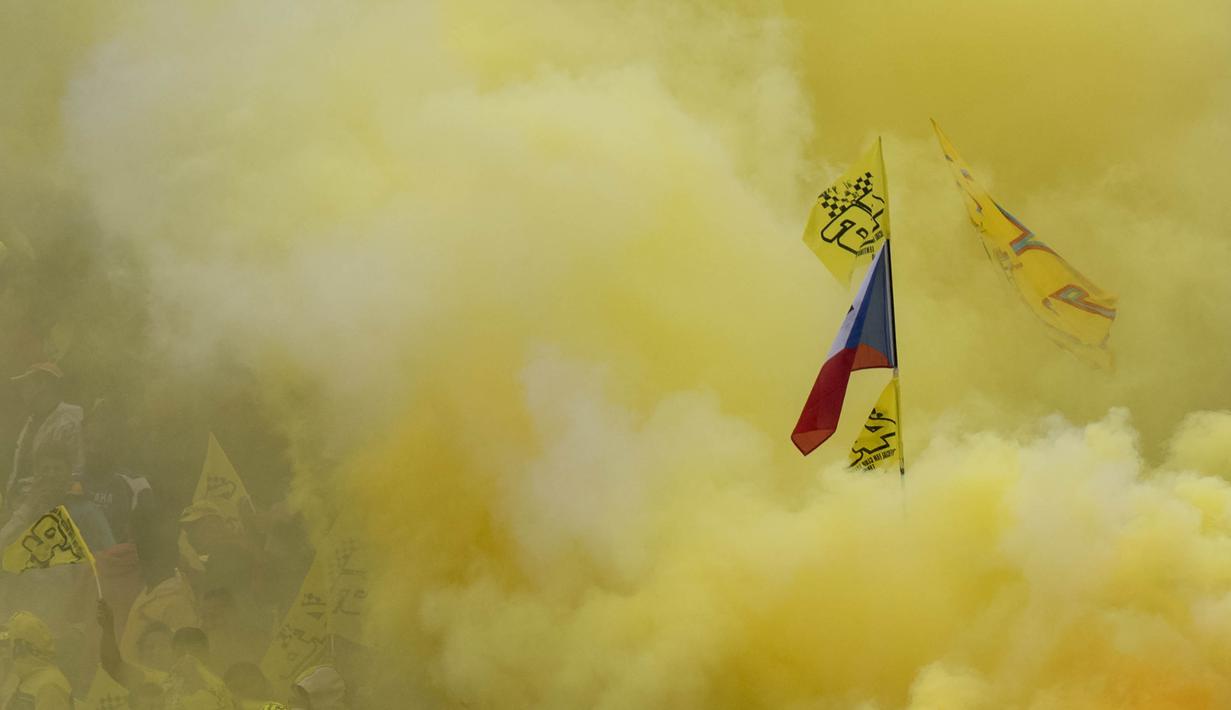 Sejumlah fans dari pebalap MotoGP, Valentino Rossi, menyalakan flare berwarna kuning ketika memberikan dukungan saat GP Ceska di Sirkuit Brno, Ceska, Minggu (21/8/2016). (AFP/Joe Klamar)