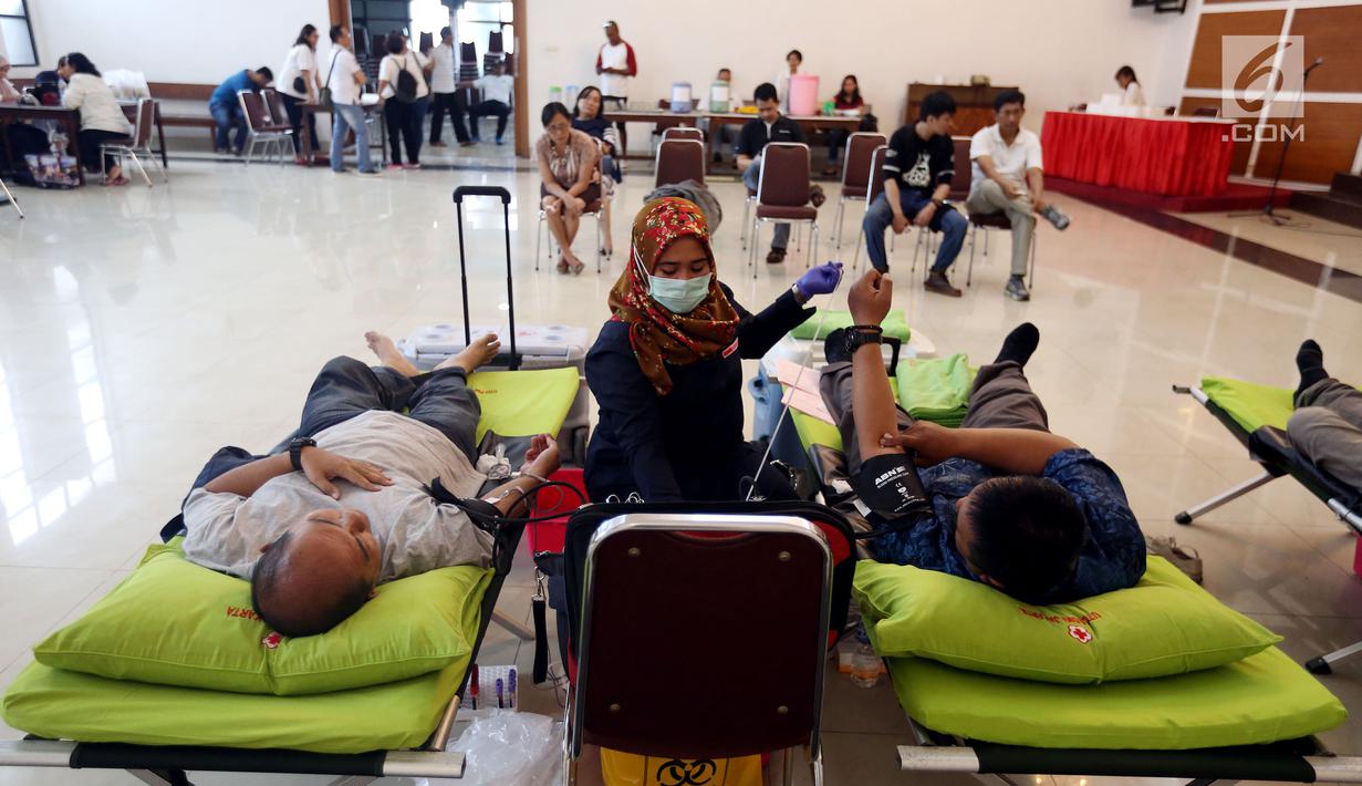Petugas muslim dari Palang Merah Indonesia (PMI) membantu Jemaat Gereja Protestan Indonesia Bagian Barat (GPIB) dalam donor darah, Jakarta, Minggu (3/12). Kegiatan tersebut diadakan dalam rangkaian acara Natal. (Liputan6.com/JohanTallo)