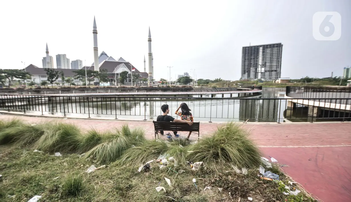 Warga duduk di bangku dengan kondisi sampah berserakan di sekeliling Waduk Mookervart, Duri Kosambi, Jakarta Barat, Senin (11/10/2021). Waduk ini berfungsi sebagai sumber resapan air dan dilengkapi SPAM untuk sumber air bersih bagi warga Rusun Pesakih.  (merdeka.com/Iqbal S. Nugroho)