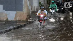 Akibat banjir tersebut membuat arus lalu lintas dan akivitas warga terhambat saat melintasi jalan. (Liputan6.com/Johan Tallo)