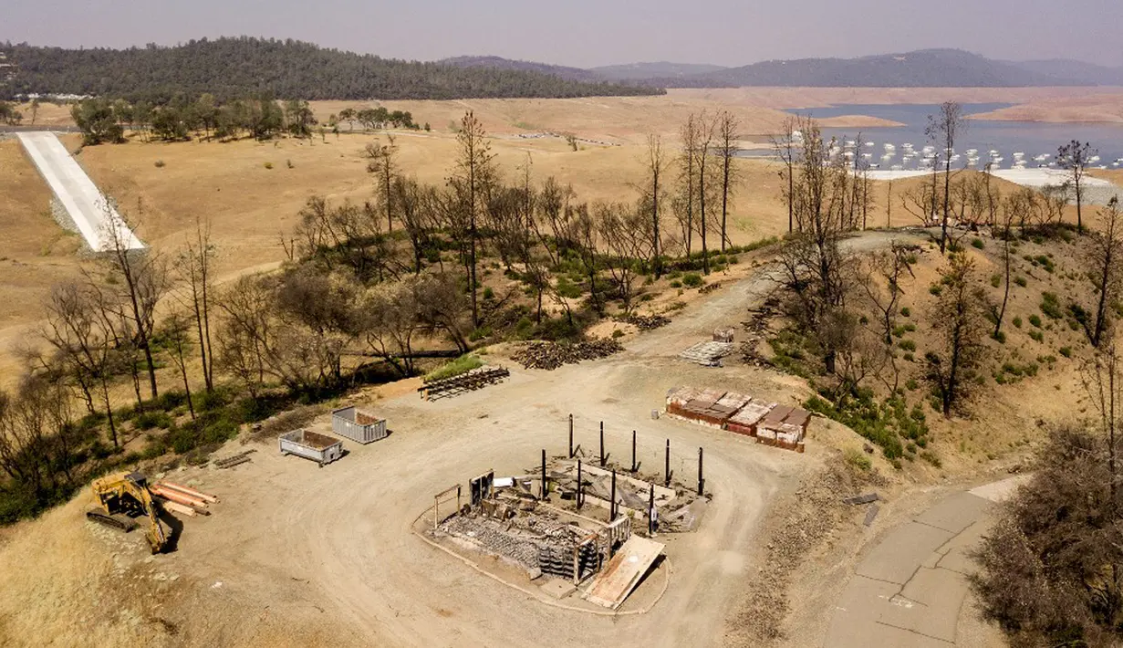 Properti yang terbakar terlihat di atas Danau Oroville yang surut di Oroville, California, Amerika Serikat, 5 September 2021. Danau Oroville saat ini hanya memiliki kapasitas air sebanyak 23 persen dan mengalami kekeringan ekstrem. (JOSH EDELSON/AFP)