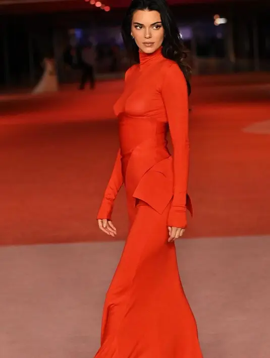 Ia memadukannya dengan korset pita diikat rapi di bagian samping. Serta rok panjangnya warna merah.  [@kendalljenner]