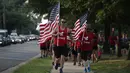 Sejumlah warga yang tergabung dalam kelompok veteran berlari sambil membawa bendera Amerika Serikat untuk menunjukan solidaritas terkait penembakan di Virginia, AS (14/6). (Alex Wong/Getty Images/AFP)