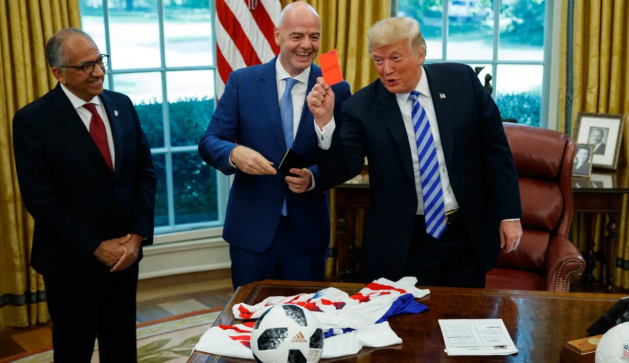 Presiden AS, Donald Trump memegang kartu merah yang diberikan presiden FIFA, Gianni Infantino (tengah) selama pertemuan di Oval Office Gedung Putih, Selasa (28/8). Presiden FIFA bertemu Trump untuk membahas kesiapan Piala Dunia 2026. (AP/Evan Vucci)