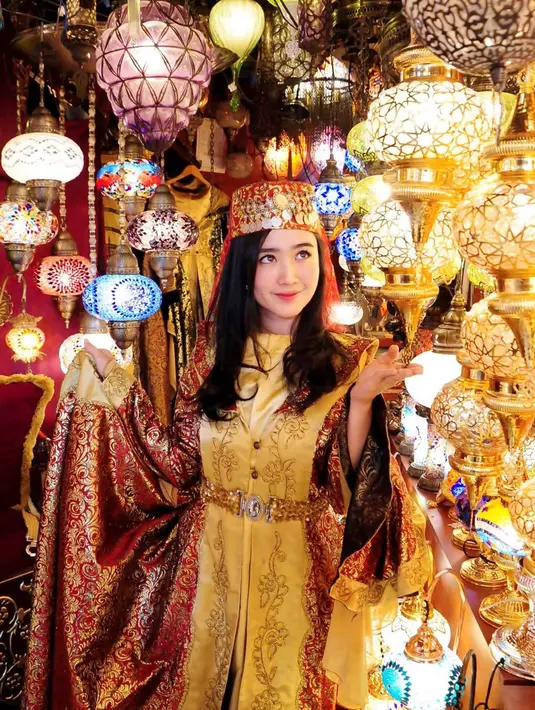 Tampil makin bersinar di antaranya lampu-lampu kaca bergaya mediterrania ini. Tampil dengan busana bak tuan putri, penampilannya pun terlihat anggun. Sudah terbiasa tampil anggun dengan berbagai gaun glamor, gaya mewahnya ini pun terlihat beda dari biasanya. (Liputan6.com/IG/@febbyrastanty)
