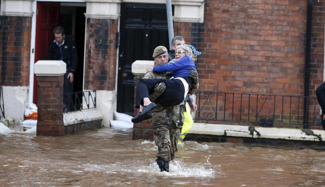 Petugas penyelamat mengevakuasi warga di Carlisle, Inggris, Minggu (6/12). Puluhan ribu rumah tidak punya listrik karena Badai Desmond yang menyebabkan banjir di Inggris utara dan sebagian wilayah Skotlandia. (REUTERS/Phil Noble)
