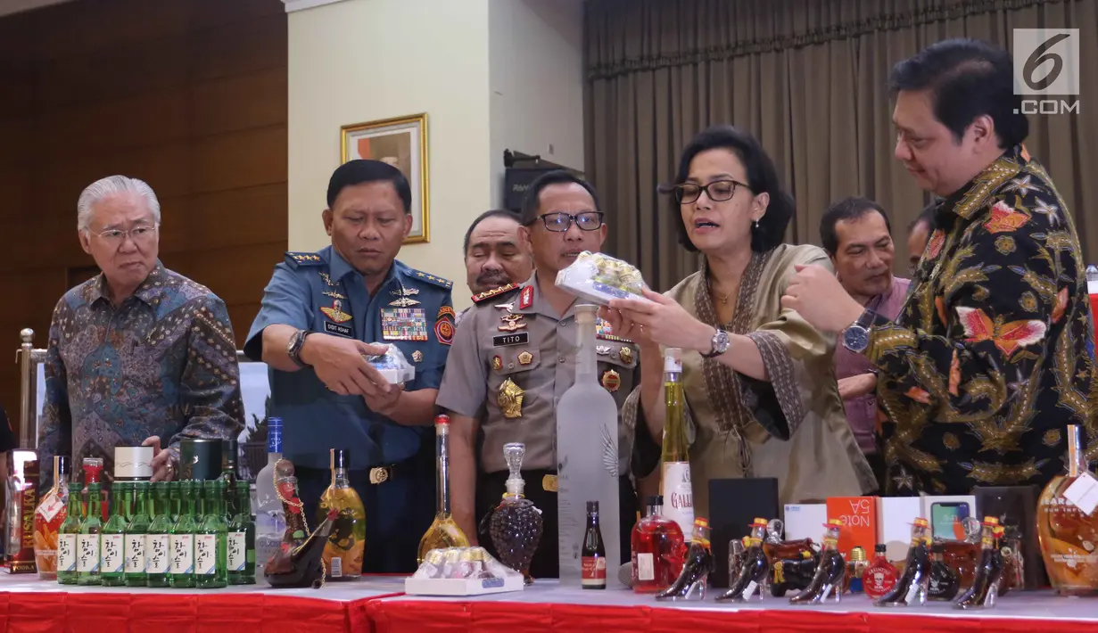 Menteri Keuangan Sri mulyani (kedua kiri) menunjukkan barang bukti hasil sitaan di Bea dan Cukai, Jakarta, Kamis (15/2). Sebanyak 142.519 botol minuman keras dan  12.919.499 batang rokok dimusnakan. (Liputan6.com/Anggan Yuniar)